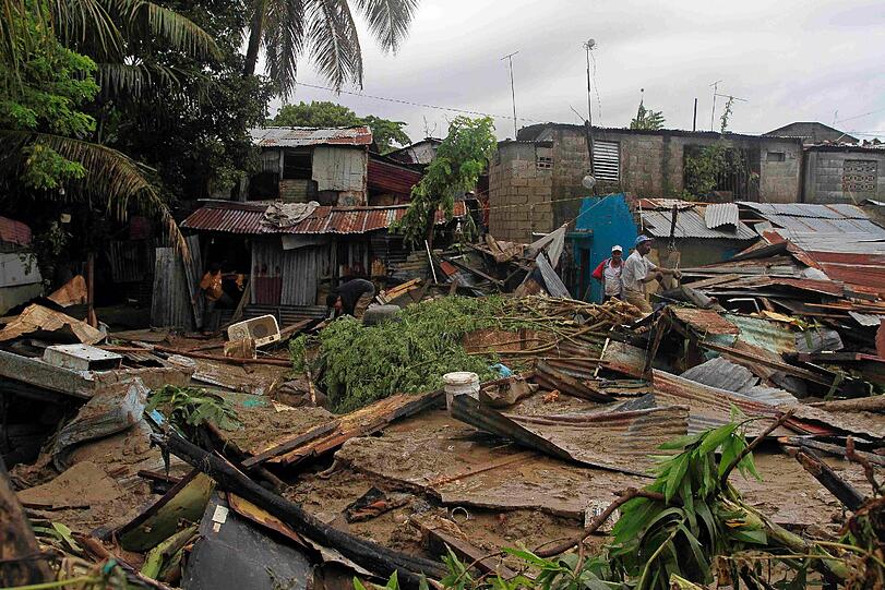 Zwischen den zerstörten Häusern suchen die Bewohner in den Trümmern nach ihrem Besitz. Der Sturm hat hier in San Cristobal (Dominikanische Republik) alles verwüstet.