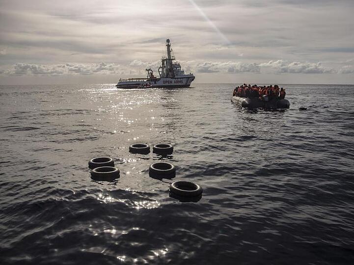 Migranten sitzen in einem Schlauchboot, nachdem sie im Mittelmeer entdeckt und gerettet wurden.