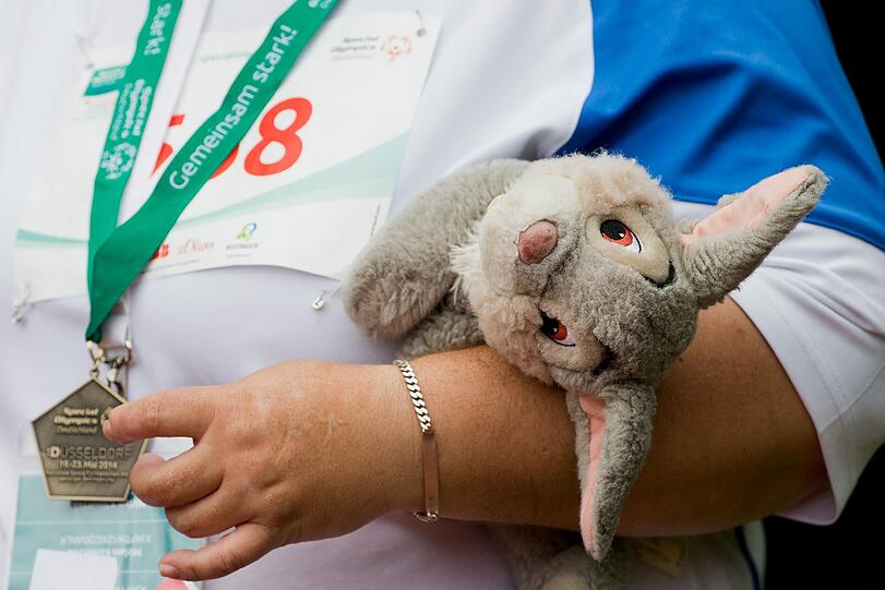 Eine Teilnehmerin steht am 21.05.2014 im Waldstadion in Düsseldorf (Nordrhein-Westfalen) bei den Special Olympics Deutschland mit ihrem Stoffesel und ihrer Bronzemedaille auf dem Podium. Hier treten geistig behinderte Athleten in verschiedenen Disziplinen wie 100 m Rollstuhl, Kugelstoßen und Speer-Wurf gegeneinander an und kämpfen um Gold, Silber und Bronze.