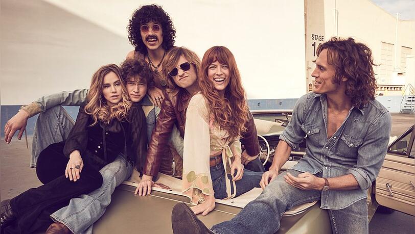 Riley Keough (zw. v. r.) und Sam Claflin (r.) spielen die beiden Hauptrollen Daisy Jones und Billy Dunne.