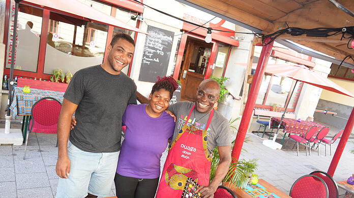 Robert Ahiagba (re.) mit seiner Nichte Marcelle und seinem Sohn Joel vor dem Makula in der Dreimühlenstraße. Hier hilft man zusammen. Wenn Ahiagba gerade nicht in der Küche steht, ratscht er mit seinen Gästen und erzählt Geschichten aus Togo.