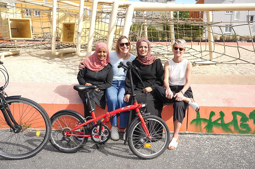 Gute Laune: Rad-Sch&uuml;lerin Jemila (28) mit den ehrenamtlichen Juno-Trainerinnen Heather, Dua&rsquo;a und Petra &ndash; mit dem roten Lern-Rad.