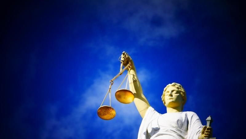 Eine Statue der Justitia hält eine Waage in ihrer Hand.