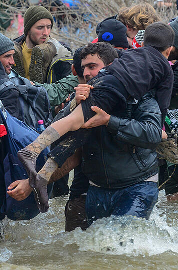 Hunderte Flüchtlinge aus dem Lager in Idomeni durchqueren einen reißenden Fluss auf griechischer Seite, um illegal nach Mazedonien zu gelangen.