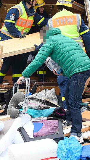 Der Besitzer des Wohnwagens (grüne Jacke) sammelt seine Habseligkeiten zusammen.