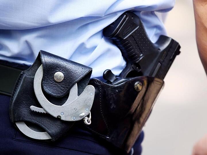 Ein Polizist trägt Handschellen und eine Pistole am Gürtel. Foto: Oliver Berg/Archivbild