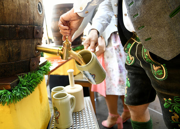 Ein Mann zapft Bier am Viktualienmarkt in einen Sonderkrug zum Start der "WirtshausWiesn 2021".