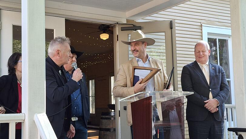 Kai Hennig (l.), der deutsche Generalkonsul in Houston, spricht zu Ministerpr&auml;sident Markus S&ouml;der, der wie ein echter Texaner eingedeckt worden ist.