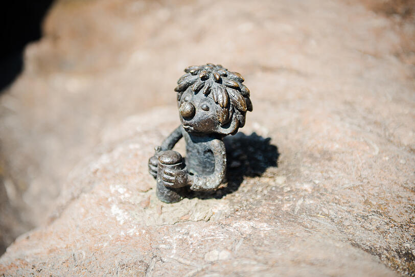 Etwa 5 bis 10 Zentimeter hoch ist die kleine Pumuckl-Figur. Der Kobold h&auml;lt so etwas wie einen Ma&szlig;krug in beiden H&auml;nden.