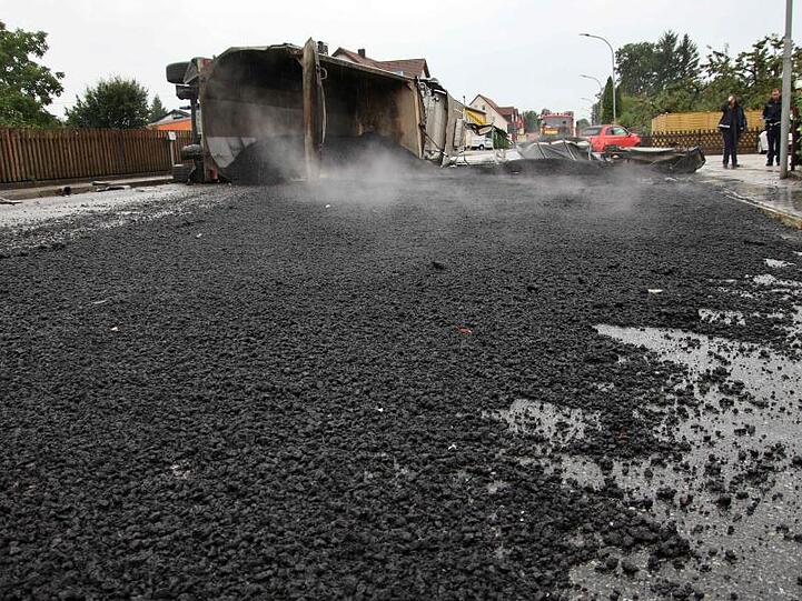 Ein Lastwagen liegt umgekippt auf der Seite auf einer Straße, über die sich großflächig Teer verteilt hat. Foto: Alexander Auer