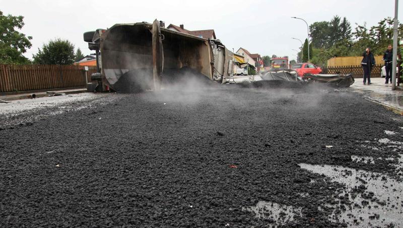 Ein Lastwagen liegt umgekippt auf der Seite auf einer Straße, über die sich großflächig Teer verteilt hat. Foto: Alexander Auer Ein Lastwagen liegt umgekippt auf der Seite auf einer Straße, über die sich großflächig Teer verteilt hat. Foto: Alexander Auer