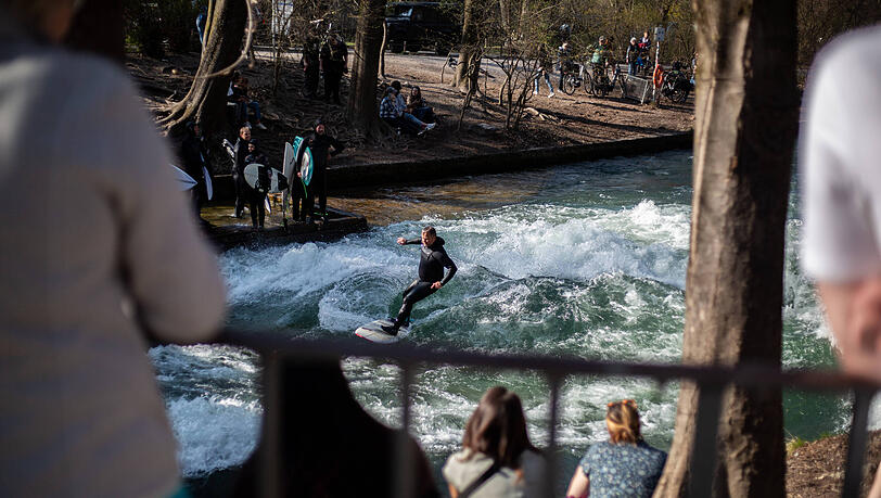 Münchner Frühlingsgrüße Ende März: Surfer und Zuschauer* tummeln sich am Eisbach.