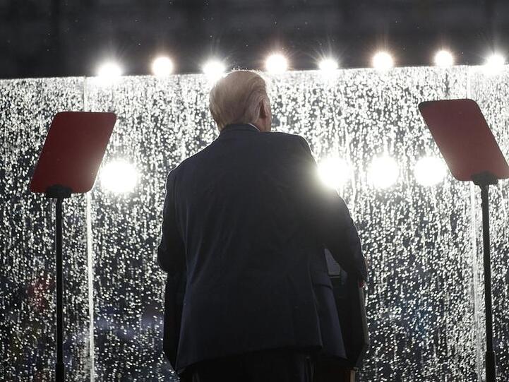 Donald Trump hält bei Regen seine Rede hinter einem Sicherheitsglas.