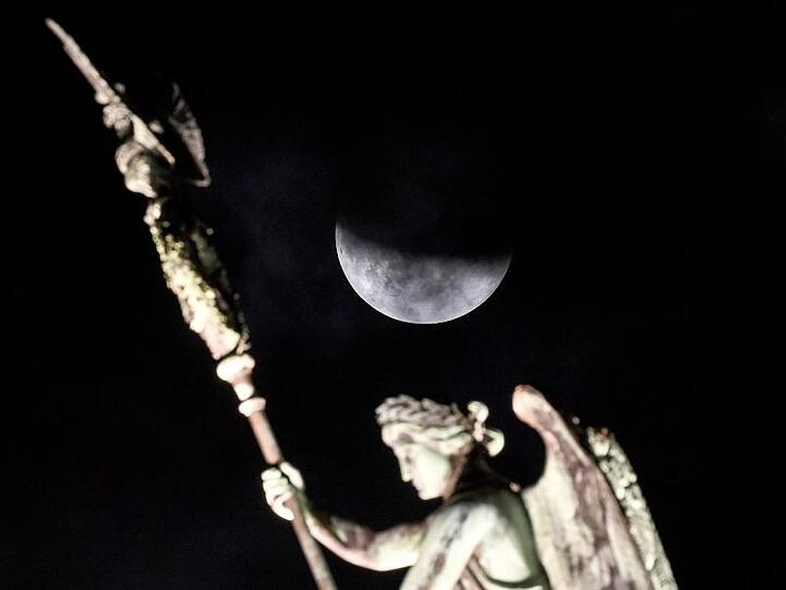 Der Mond ist während der partiellen Mondfinsternis hinter der Quadriga des Brandenburger Tors zu sehen.