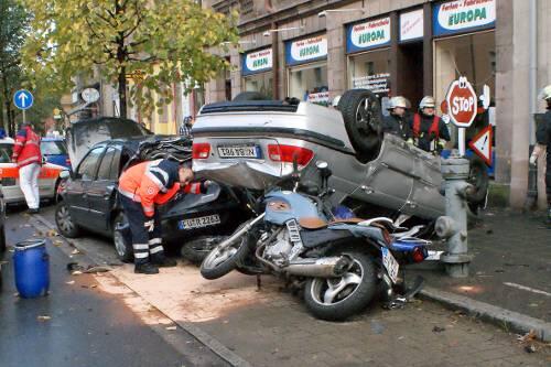 Der BMW-Fahrer wurde bei dem Landung auf dem Dach zum Glück nur leicht verletzt. Die in der Parkbucht abgestellten Autos und Motorräder der Fahrschule jedoch haben jetzt nur noch Schrottwert.