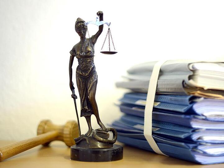 Justitia mit Holzhammer und Aktenstapel. Foto: Volker Hartmann/dpa