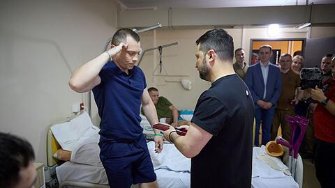 Präsident Selenskyj (r) überreicht während eines Besuchs in einem Zentrum für Rehabilitationsmedizin in Iwano-Frankiwsk einen Militärorden an einen verwundeten Soldaten.