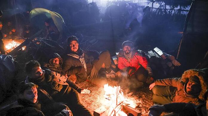 Migranten wärmen sich an einem Feuer an der belarussisch-polnischen Grenze auf.