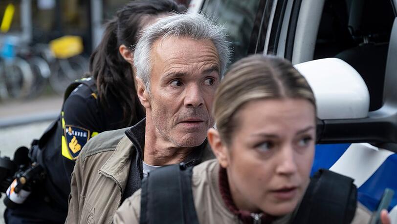 "Der Amsterdam-Krimi: Der falsche Tote": Alex Pollack (Hannes Jaenicke) und seine Kollegin Zoe (Rose-Anne van Elswijk) warten, bis die bewaffneten Täter rauskommen.