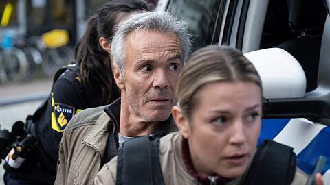 "Der Amsterdam-Krimi: Der falsche Tote": Alex Pollack (Hannes Jaenicke) und seine Kollegin Zoe (Rose-Anne van Elswijk) warten, bis die bewaffneten Täter rauskommen.
