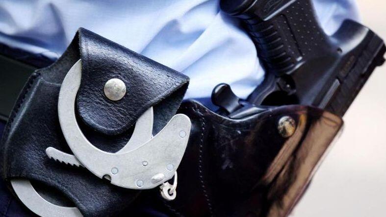 Ein Polizist mit Handschellen und Pistole am Gürtel. Foto: Oliver Berg/Archiv