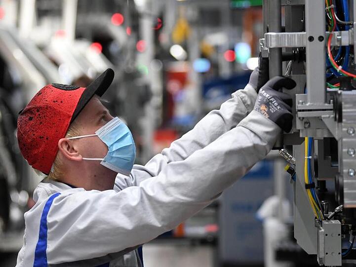 Ein Mitarbeiter von Volkswagen Sachsen arbeitet in der Montage des ID.3 im Fahrzeugwerk mit Mundschutz.