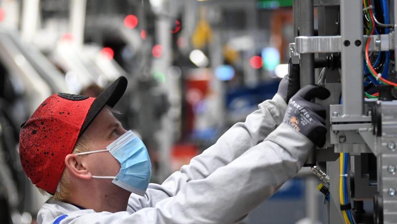 Ein Mitarbeiter von Volkswagen Sachsen arbeitet in der Montage des ID.3 im Fahrzeugwerk mit Mundschutz. Ein Mitarbeiter von Volkswagen Sachsen arbeitet in der Montage des ID.3 im Fahrzeugwerk mit Mundschutz.