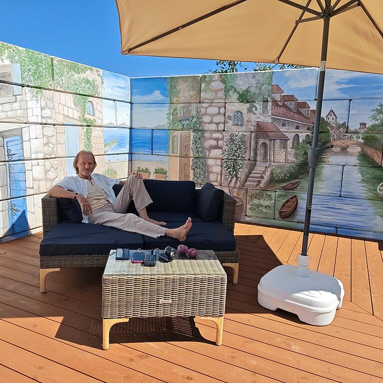 Eisi Gulp: Kraft tanken dahoam vor seiner neu errichteten Gartenwand mit Illusionsmalerei von Pit Zaepernick.