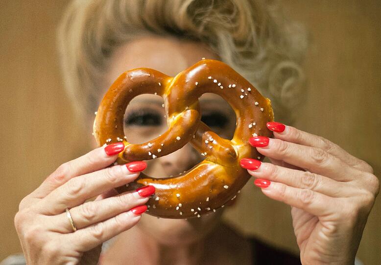 Die Besitzerin der Bäckerei Hoffmann, Anett Hoffmann, hält sich am 12.09.2012 in München (Oberbayern) eine Brezel vor ihr Gesicht. Der Markt für kleine Bäckereien wir immer härter. Bäckermeister müssen kreativ sein, um sich gegenüber Backshops und Discountern zu beweisen.