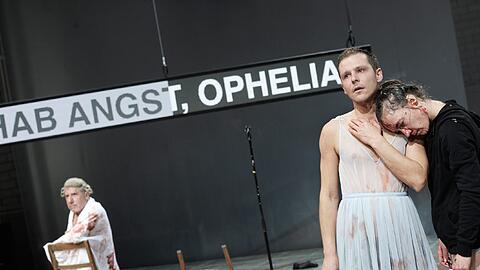 Drei Darsteller und ein Musiker spielen abwechselnd alle Rollen. In dieser Szene von Christopher Rüpings Inszenierung ist Nils Kahnwald gerade Ophelia, Katja Bürkle spielt den Hamlet. Im Hintergrund Walter Hess - er ist unter anderem Polonius, Claudius und Gertrud.