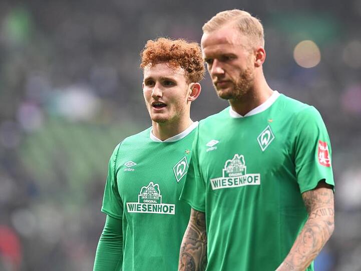 Die Bremer Kevin Vogt (r) und Josh Sargent laufen enttäuscht über den Rasen.