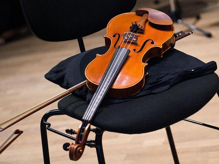 Eine Geige liegt in einer Probenpause im Konzertsaal der Philharmonie Bad Reichenhall auf einem Stuhl.