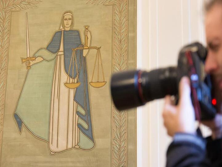 Ein Fotograf vor dem Bild der Justitia. Foto: Friso Gentsch/dpa/Archivbild