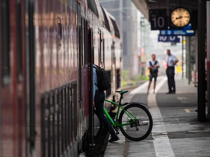 Ein Mann steigt mit seinem Fahrrad in einen Zug.