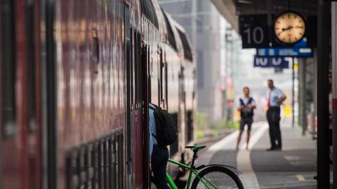 Ein Mann steigt mit seinem Fahrrad in einen Zug.