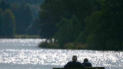 Ein Pärchen auf einer Sitzbank ist durch die glitzernde Wasseroberfläche als Silhouette zu erkennen. Foto: Nicolas Armer