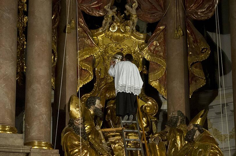 Der Mesner des Alten Peter in der Münchener Innenstadt nimmt der Petrus-Figur die Tiara vom Haupt.