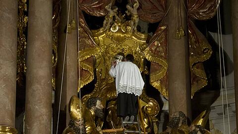 Der Mesner des Alten Peter in der Münchener Innenstadt nimmt der Petrus-Figur die Tiara vom Haupt.