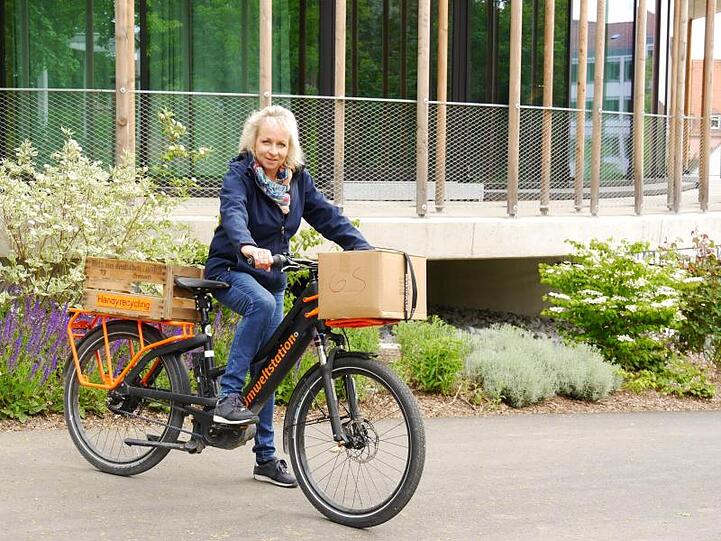 Anja Knieper, die Leiterin der Umweltstation, sitzt auf einem Fahrrad vor der Station. Foto: Jakob Sänger/Umweltstation/dpa