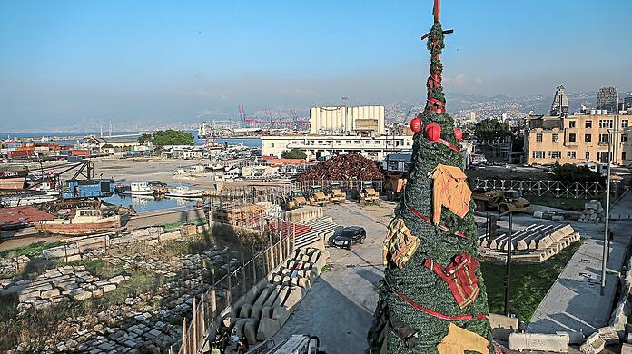 Ein mit Kleidung und Ausrüstung von Ersthelfern und Feuerwehrleuten geschmückter Weihnachtsbaum am Eingang des zerstörten Beiruter Hafens erinnert an Feuerwehrleute, die am 4. August 2020 bei der Explosion im Hafen von Beirut ihr Leben verloren haben.