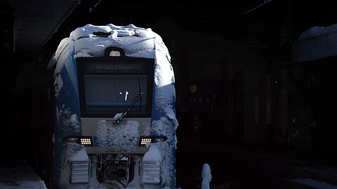 Ein mit Schnee bedeckter Regionalzug steht im Hauptbahnhof.