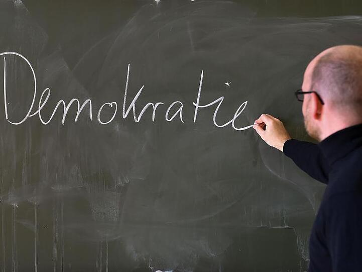Andreas Steiner, Schulleiter der Fichtenberg-Oberschule im Berliner Steglitz, schreibt an der Tafel das Wort "Demokratie".