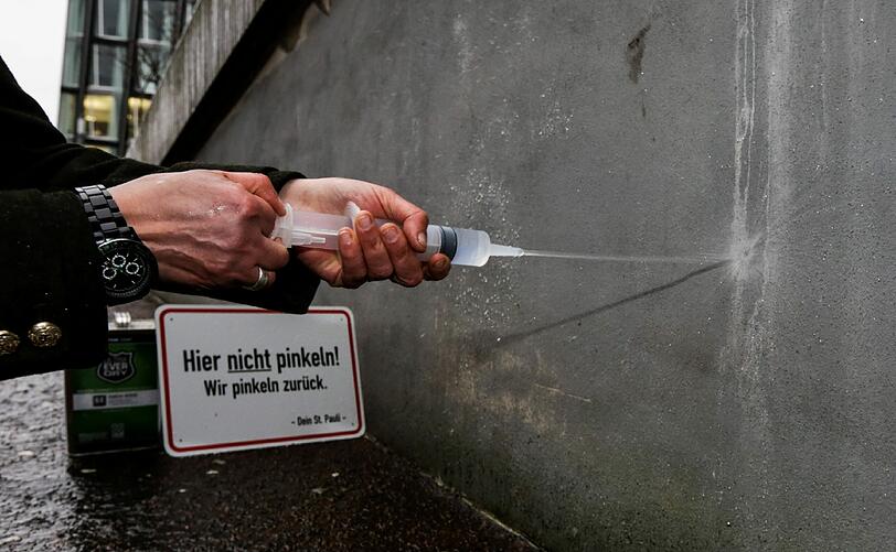 Quartiermanagerin der Reeperbahn, Julia Staron, demonstriert wie der Anti-Pissel-Lack funktioniert.