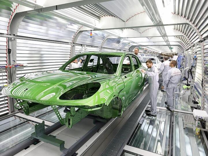 Ein Mitarbeiter prüft den Lack an einem Porsche Macan in der Lackiererei im Porsche-Werk Leipzig. Foto: Jan Woitas/Archiv