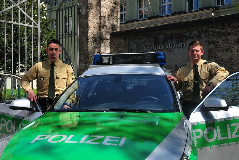 Die beiden Polizeibeamten vor ihrem Dienstwagen.
