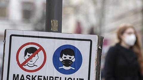 Plakate erinnern in einer fußgängerzone an die Einhaltung der Maskenpflicht.