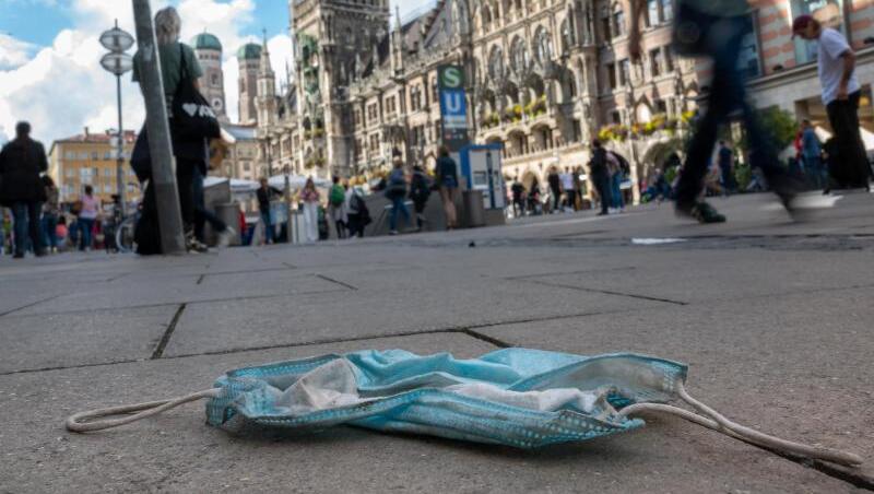 Eine getragene Mundschutzmaske liegt in der Münchener Innenstadt auf dem Gehweg. Seit Mittwoch ist die Maskenpflicht in Teilen der Münchner Innenstadt aufgehoben.