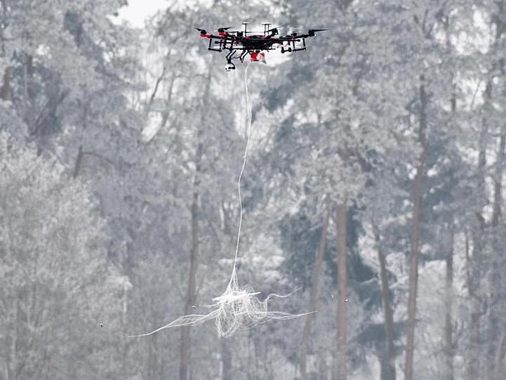Eine Jagddrohne wirft bei einem Präsentationstag der Bundeswehr über einer anderen Drohne ein Netz ab. Foto: Matthias Balk