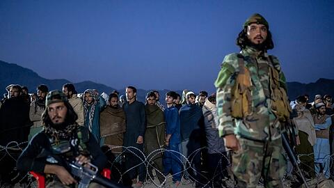 Taliban-Kämpfer stehen Wache, während afghanische Flüchtlinge in einem Lager nahe der pakistanisch-afghanischen Grenze anstehen, um sich registrieren zu lassen.