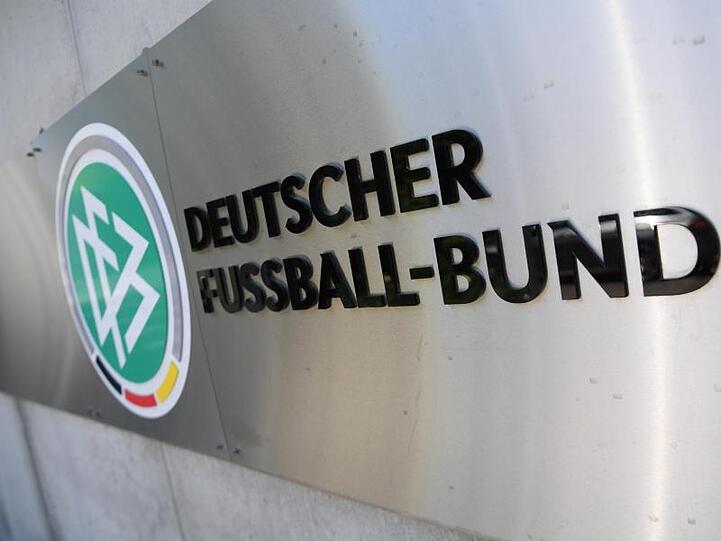 DFB-Logo und Schriftzug sind vor der Zentrale des Deutschen Fußball-Bundes (DFB) an einer Mauer platziert. Foto: Arne Dedert/dpa/Archivbild